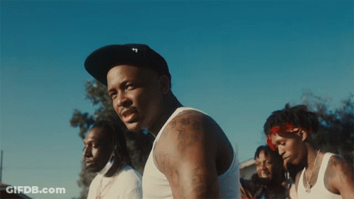 A Man Wearing A Hat With The Letter T On It Stands In Front Of A Group Of Men GIF