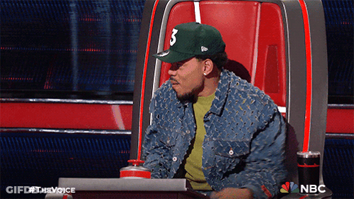 A Man Wearing A Hat With The Number 3 On It Sits In A Chair GIF