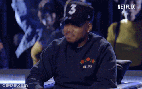 A Man Wearing A Hat With The Number 3 On It Sits In A Chair GIF