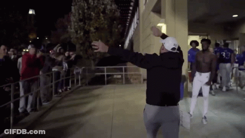A Man Wearing A Hat With The Number 33 On It Stands In Front Of A Crowd Of People GIF
