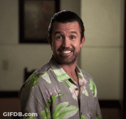 A Man Wearing A Hawaiian Shirt Is Smiling And Looking At The Camera GIF