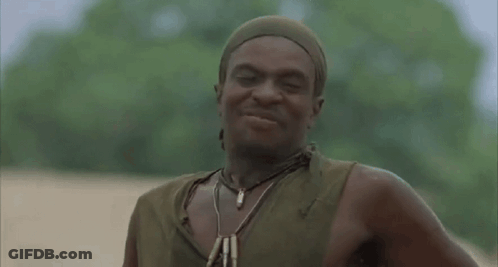 A Man Wearing A Head Scarf And A Necklace Is Standing In The Dirt . GIF