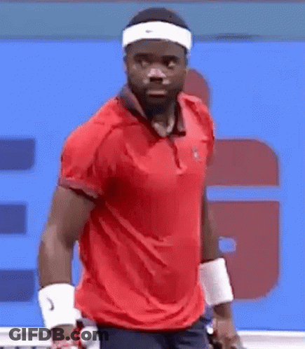A Man Wearing A Headband And A Red Shirt Is Playing Tennis On A Tennis Court . GIF
