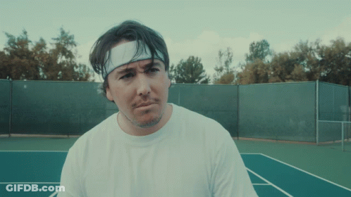 A Man Wearing A Headband And A White Shirt Is Standing On A Tennis Court GIF
