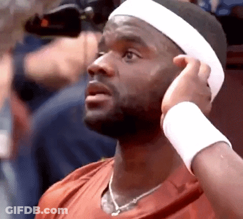 A Man Wearing A Headband And A Wristband Adjusts His Hair . GIF