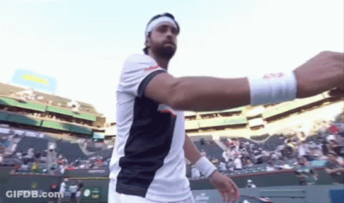 A Man Wearing A Headband And A Wristband Is Standing On A Tennis Court With A Rolex Sign In The Background GIF
