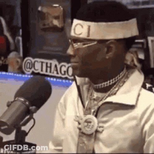 A Man Wearing A Headband And Sunglasses Is Sitting In Front Of A Microphone . GIF