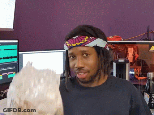 A Man Wearing A Headband Holds A Bag Of Popcorn In Front Of A Purple Wall GIF