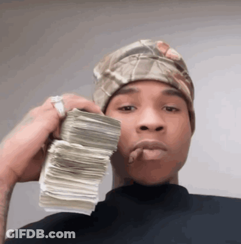 A Man Wearing A Headband Holds A Stack Of Money In His Hand GIF