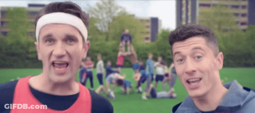 A Man Wearing A Headband Stands Next To Another Man In A Blue Shirt GIF