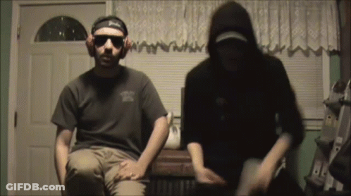 A Man Wearing A Headband That Says Budweiser Is Sitting Next To Another Man GIF