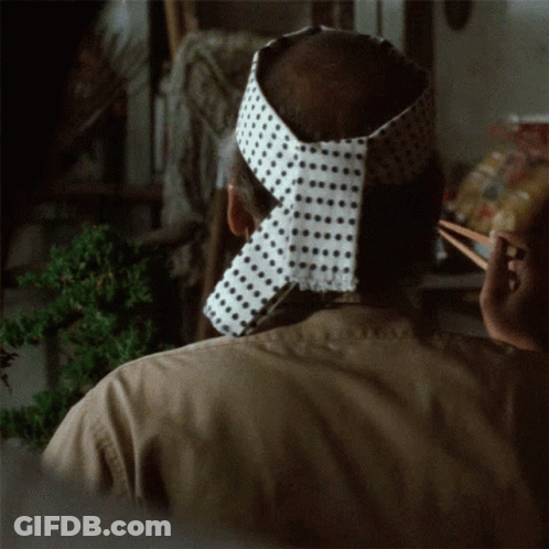 A Man Wearing A Headband With Polka Dots On It Is Holding Chopsticks GIF