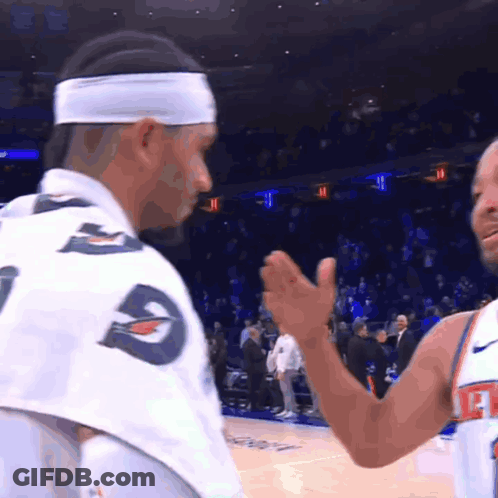 A Man Wearing A Headband With The Letter G On It Talks To Another Man GIF
