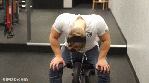 A Man Wearing A Headband With The Letter R On It Sits On A Bench In A Gym GIF