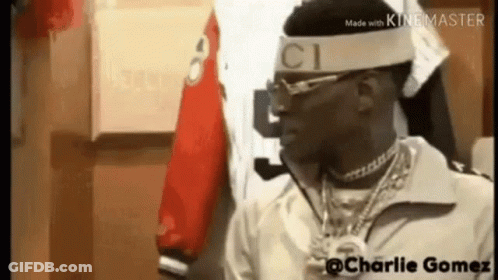 A Man Wearing A Headband With The Word Gucci On It Is Standing In A Room . GIF