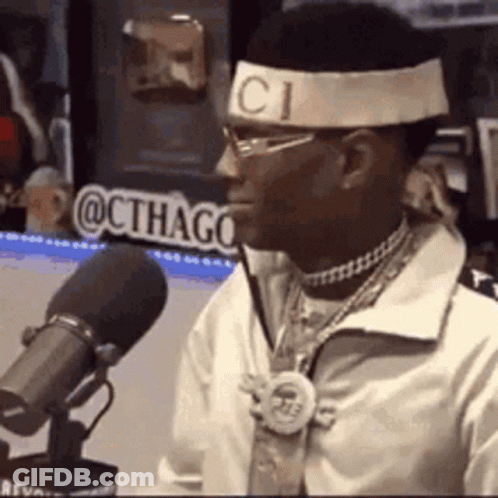 A Man Wearing A Headband With The Word Gucci On It Is Talking Into A Microphone . GIF