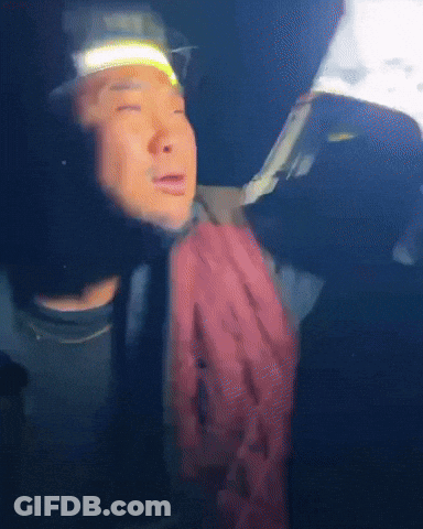 A Man Wearing A Headlamp And A Scarf Looks At Something GIF