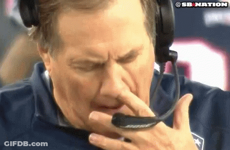 A Man Wearing A Headset Is Holding His Nose While Talking On A Phone . GIF