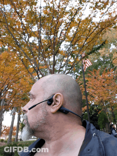 A Man Wearing A Headset Is Standing In Front Of Trees GIF