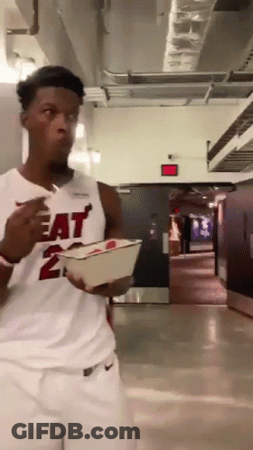 A Man Wearing A Heat Jersey Is Eating Something GIF