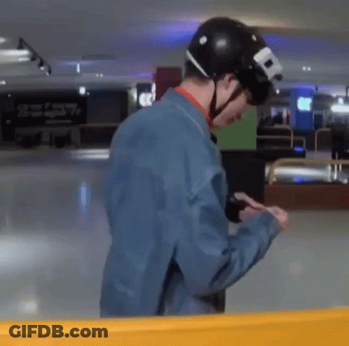 A Man Wearing A Helmet And A Blue Jacket Is Looking At His Cell Phone . GIF
