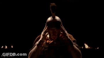 A Man Wearing A Helmet And A Hood Is Looking At The Camera In A Dark Room . GIF