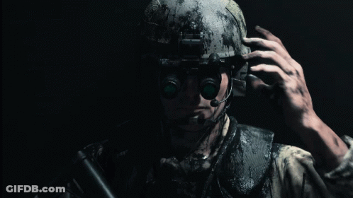 A Man Wearing A Helmet And A Microphone Holds A Gun In His Hand GIF