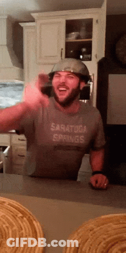 A Man Wearing A Helmet And A Saratoga Springs Shirt Laughs GIF