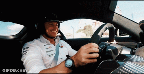 A Man Wearing A Helmet And A Shirt That Says Ubs Is Driving A Car GIF