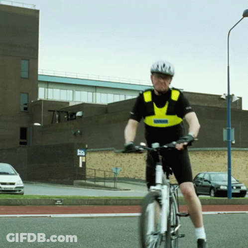 A Man Wearing A Helmet And A Vest That Says Police On It Is Riding A Bike GIF