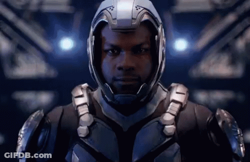 A Man Wearing A Helmet And Armor Is Standing In A Dark Room . GIF