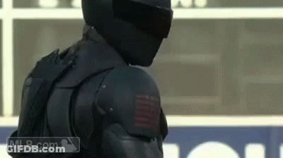 A Man Wearing A Helmet And Armor Is Standing On A Field . GIF