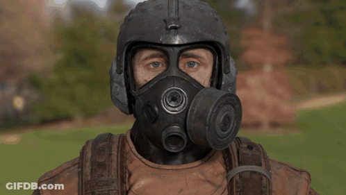 A Man Wearing A Helmet And Gas Mask Looks At The Camera GIF