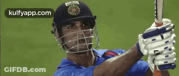 A Man Wearing A Helmet And Gloves Is Holding A Bat . GIF