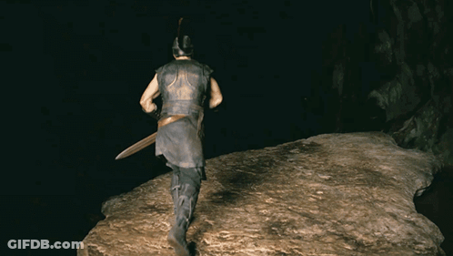 A Man Wearing A Helmet And Holding A Sword Is Walking On A Rock In The Dark GIF