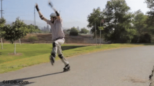 A Man Wearing A Helmet And Knee Pads Is Rollerblading Down A Path GIF