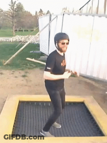 A Man Wearing A Helmet And Sunglasses Is Standing On A Trampoline GIF