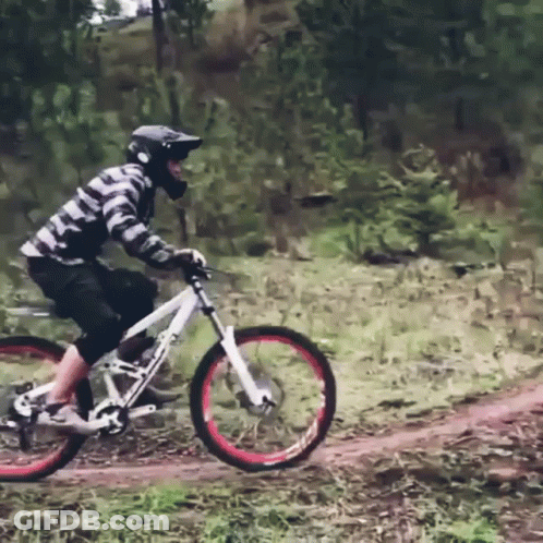 A Man Wearing A Helmet Is Riding A Bike On A Dirt Path GIF