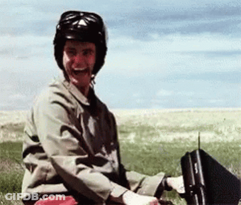 A Man Wearing A Helmet Is Sitting In A Field With A Briefcase GIF