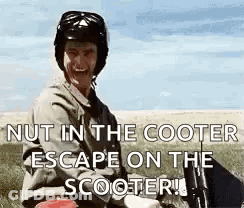 A Man Wearing A Helmet Is Sitting On A Scooter In A Field And Smiling . GIF
