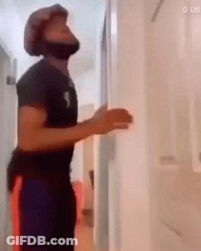 A Man Wearing A Helmet Is Standing In A Hallway . GIF