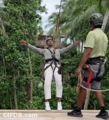 A Man Wearing A Helmet Is Standing Next To A Woman Wearing A Helmet On A Zip Line GIF