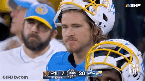 A Man Wearing A Helmet Sits In The Stands Watching A Football Game GIF