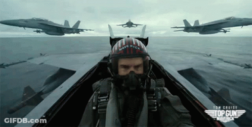 A Man Wearing A Helmet That Says Maverick Is Flying A Plane GIF