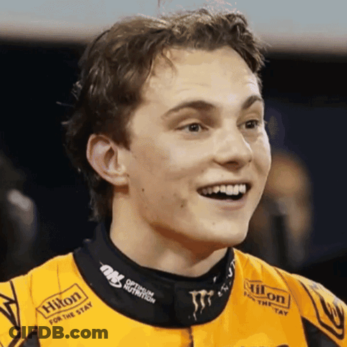 A Man Wearing A Hilton For The Stay Shirt Smiles For The Camera GIF