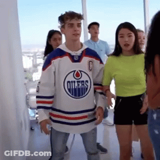 A Man Wearing A Hockey Jersey Is Standing Next To A Woman In A Neon Green Shirt . GIF