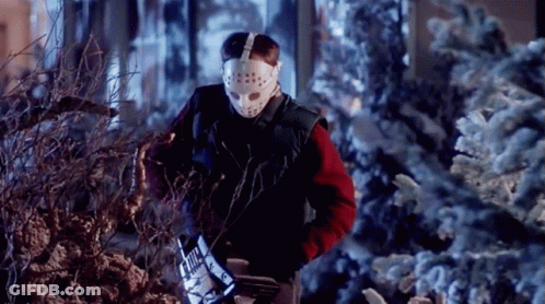A Man Wearing A Hockey Mask And Gloves Is Cutting A Tree GIF