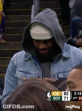 A Man Wearing A Hooded Jacket And A Beanie Stands In Front Of A Scoreboard That Says Lal Bos 71 GIF