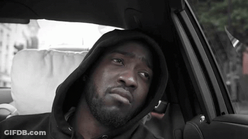 A Man Wearing A Hooded Sweatshirt Is Sitting In A Car GIF