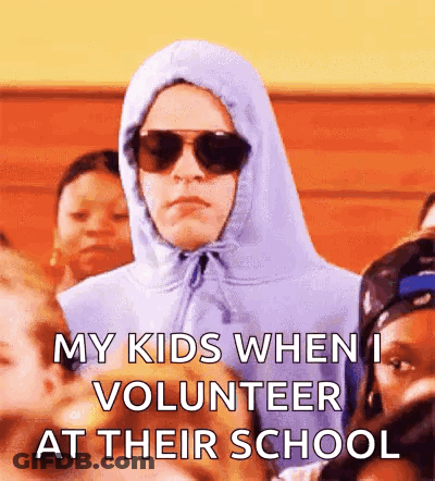 A Man Wearing A Hoodie And Sunglasses Is Standing In A Crowd Of Children . GIF